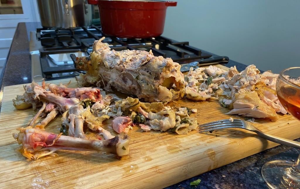 The remaining scraps and exposed bones of the now-eaten chicken, sitting on the cutting board.