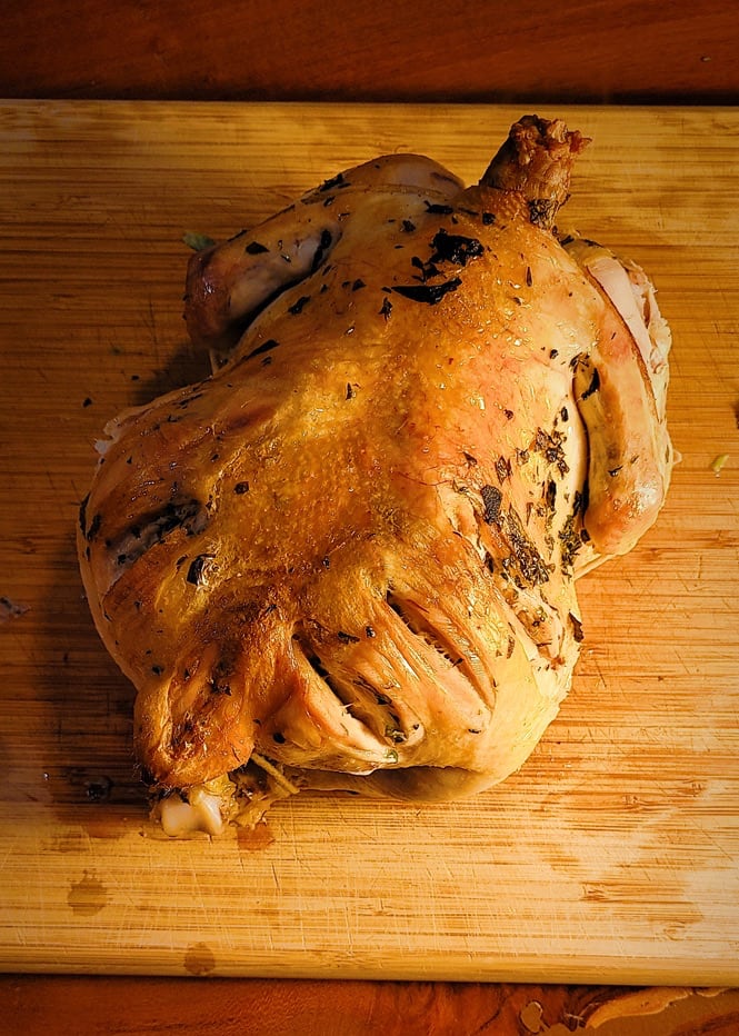 A photo of a roasted chicken, on a warmly lit wood table